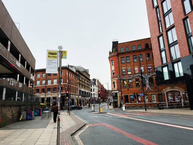 Manchester, İngiltere - 26 Ocak 2026: Tuğla mimarisi, trafik işaretleri ve yayalarla dolu canlı bir Manchester caddesi.