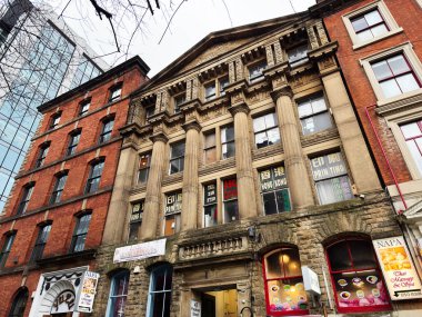 Manchester, İngiltere - 29 Ocak 2026: Manchester 'daki tarihi sokak sahnesi büyük tuğlalı bina, Çin mağazası pencereleri ve Asya renkli tabelalar.