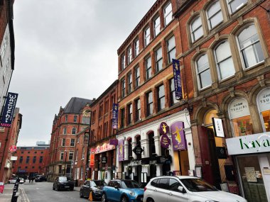 Manchester, İngiltere - 29 Ocak 2026: Manchester, İngiltere 'de canlı bir şehir sokak manzarası, tuğla cepheleri, Tayland tabelası ve park halindeki arabaların yer aldığı.