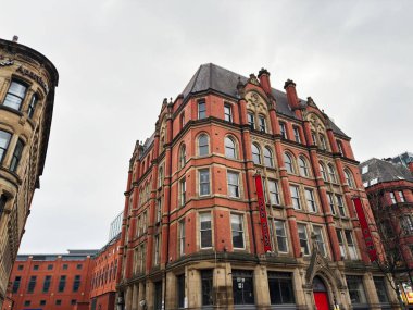 Manchester, İngiltere - 29 Ocak 2026: Kemerli camlı kırmızı tuğla cephe ve Manchester caddesinde Yang Sing afişleri.