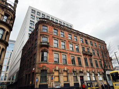 Manchester, İngiltere - 29 Ocak 2026: Manchester caddesindeki kırmızı tuğlalı bina, çıplak ağaçlı şehir manzarası.