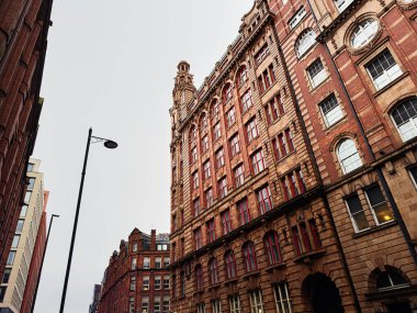 Manchester 'da süslü detayları ve şehir atmosferiyle dolu uzun kırmızı tuğlalı binalar.