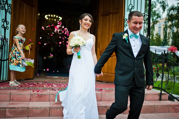 Hochzeitspaar verlässt Kirche auf Rosenblättern — Stockfoto