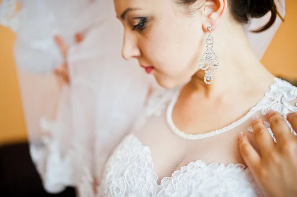 Oorbellen op mooie jonge brunette bruid — Stockfoto