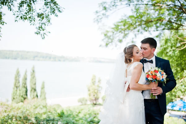 Esküvői pár háttérben zöld fák, és a tó — Stock Fotó