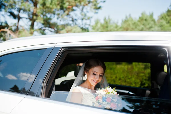 Noiva com bouquet olhando da janela do carro — Fotografia de Stock