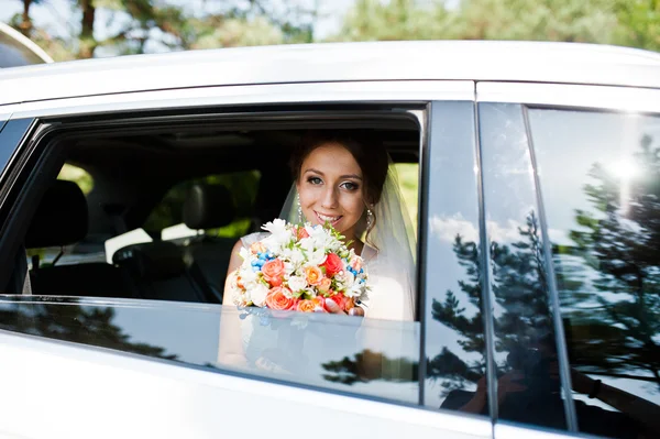 Mariée avec bouquet regardant par la fenêtre de la voiture — Photo