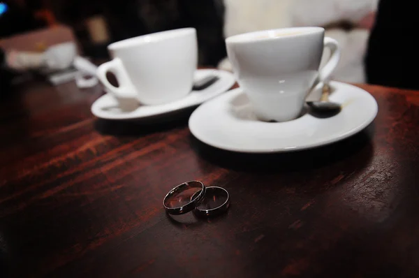 Dos anillos de boda de plata fondo tazas de café — Foto de Stock