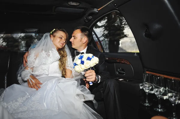 Bruidspaar zittend op limousine — Stockfoto