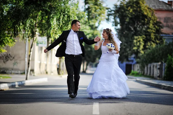 Casamento casal correndo e se divertir na estrada — Fotografia de Stock