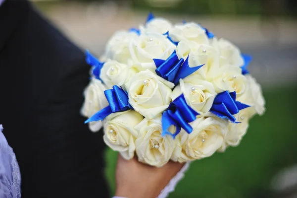 Brautstrauß mit weißer Rose und blauer Schleife zur Hand der Braut — Stockfoto