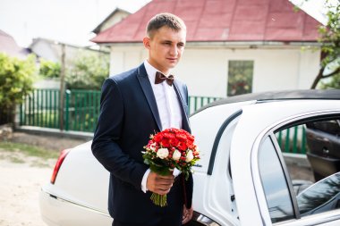 Sedan yakınındaki buket ile damat kalmak