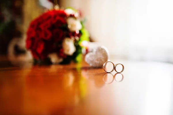 Red wedding bouquet  with rings on wooden table — Stock Photo, Image