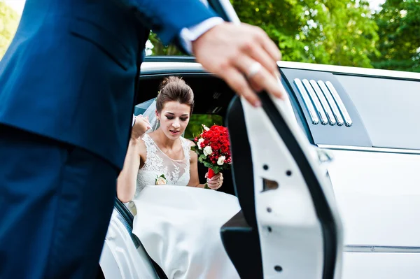 Groom open door of limousine and take hand to bride — Stock Photo, Image