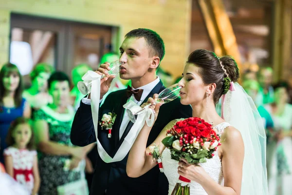 Невеста и жених пьют из свадебных бокалов шампанского — стоковое фото