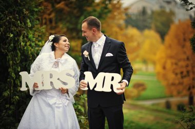 Happy wedding couple in autumn day with sign mrs & mr clipart