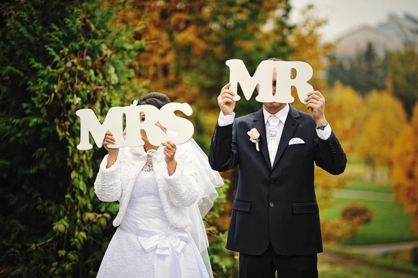 Happy wedding couple in autumn day with sign mrs & mr — Stock Photo, Image