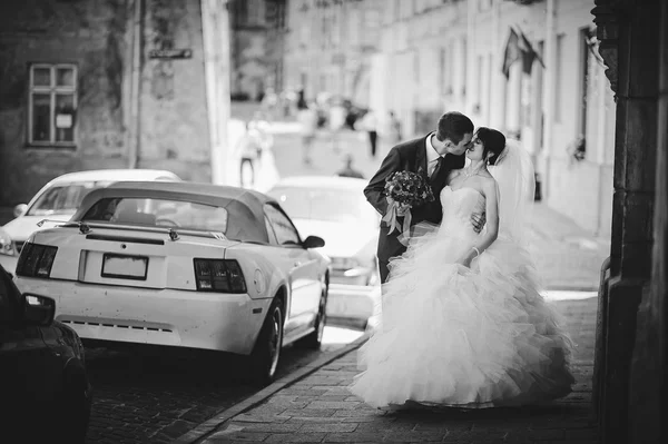 Beijando recém-casados fundo músculo carro — Fotografia de Stock