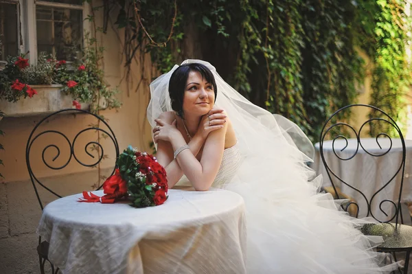 Thinking bride sitting on table outdoor — Stock Photo, Image