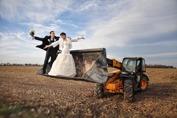 Casal de casamento feliz e engraçado em um trator colher — Fotografia de Stock