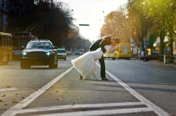 Besos pareja de boda en el medio de la carretera — Foto de Stock