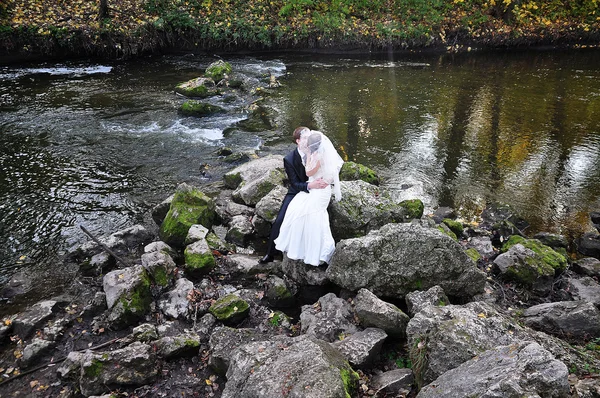 Весільна пара залишається на камені річки — стокове фото