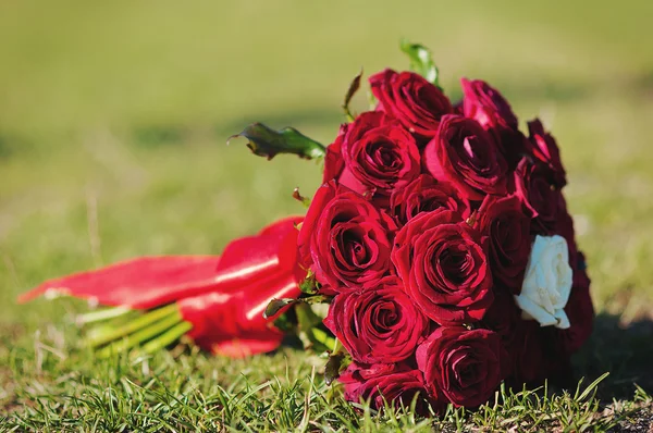 Hochzeitsstrauß aus roten Rosen auf Gras — Stockfoto