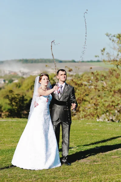 Свадебная пара наливает шампанское из бокалов — стоковое фото