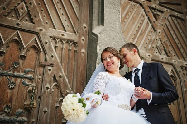 Bröllopsparet nära gamla trädörr i katolska kyrkan — Stockfoto