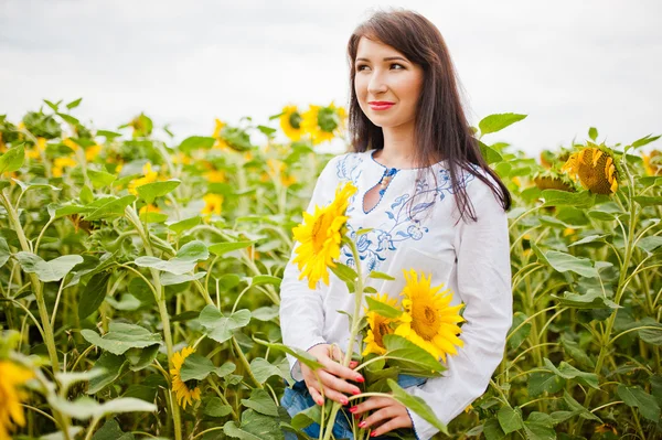 Ung brunett flicka på fält av solrosor — Stockfoto