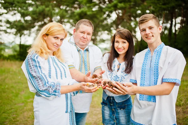 Happy family on pine forest holding cones at hand — Stock Photo, Image