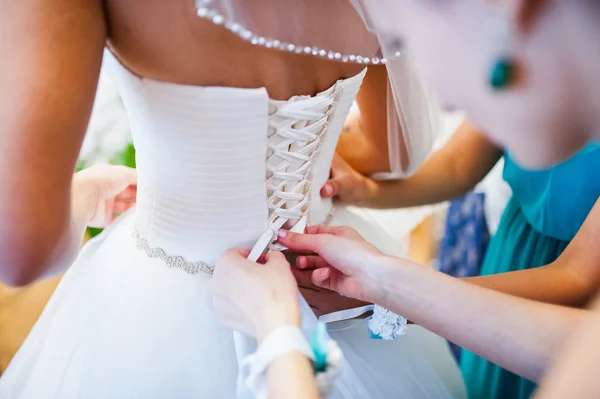 Družička uvázat tkaničky na zadní straně svatební šaty — Stock fotografie