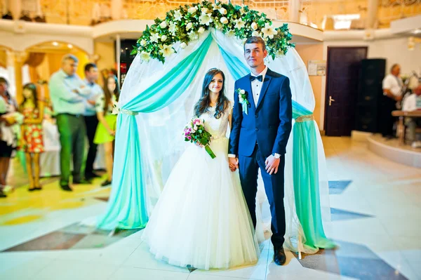 Casamento casal estadia sob arco no restaurante — Fotografia de Stock