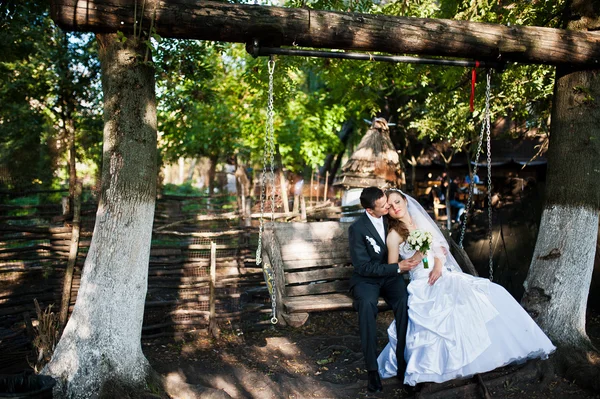 Весільна пара сидить на великих дерев'яних гойдалках — стокове фото