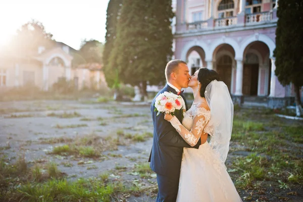 Casal de casamento elegante perto da velha casa rosa vintage com colunas — Fotografia de Stock