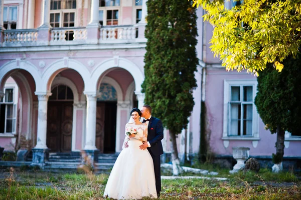 Stilvolles Hochzeitspaar in der Nähe von altem rosa Haus mit Säulen — Stockfoto