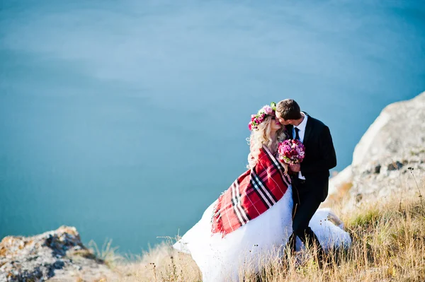 Sposa affascinante in una ghirlanda ed elegante sposo su paesaggi di mo — Foto Stock