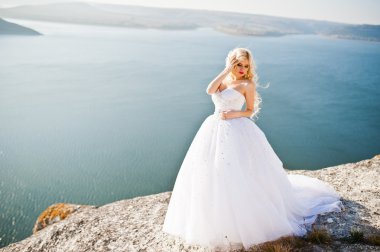 Charming blonde bride on landscapes of mountains, water and blue
