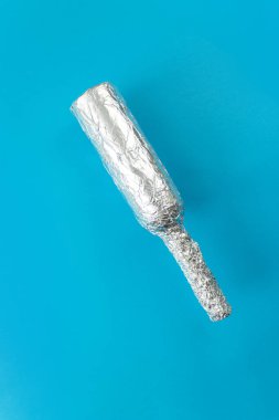 İnce folyoya sarılı şişe mavi arka plana düşüyor..