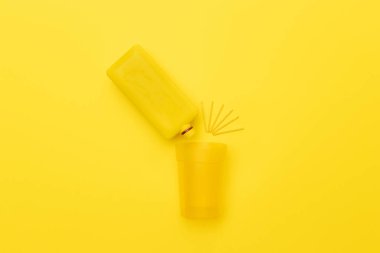 Sarı arka planda sarı ahşap sıçrama işareti olan sarı bir bardağa dökülüyor. Yaratıcı, soyut üst görünüm.