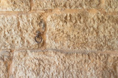 Paslı demir halkayla kaplı taş parçalarından oluşan antik bir duvar.