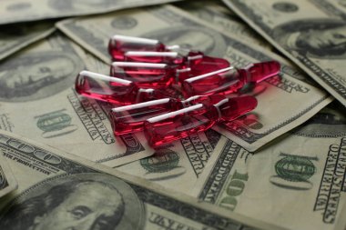 Yüz dolarlık banknotların arka planına karşı kırmızı aşılı pek çok ampul