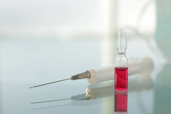 Syringe and vial with vaccine on glass table in hospital