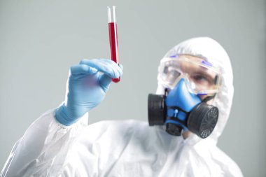 Koruyucu tıbbi giysili bir adam elinde bir test tüpü tutuyor. Coronavirüs 'e karşı açık aşı kavramı