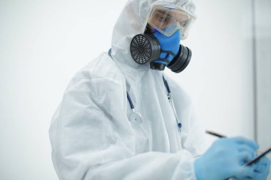 Tablet ve steteskoplu koruyucu giysili doktor.