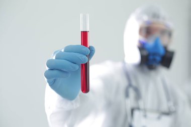 Koruyucu tıbbi giysili bir adam elinde bir test tüpü tutuyor. Coronavirüs 'e karşı açık aşı kavramı