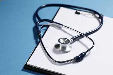 Mavi arka plandaki hastaları kaydetmek için tıbbi steteskop ve tablet