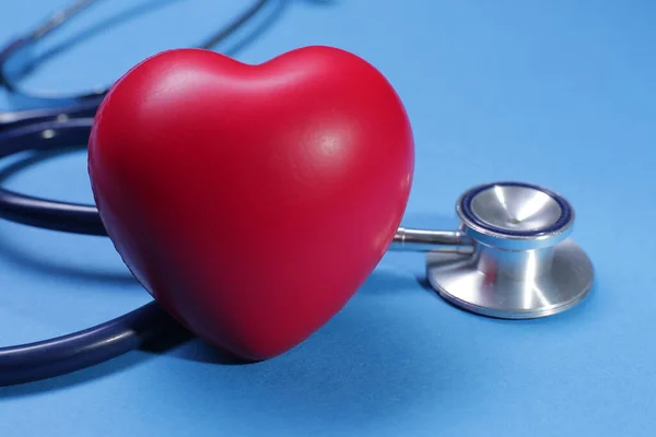 Kırmızı kalp şekli ve mavi arka planda tıbbi steteskop.
