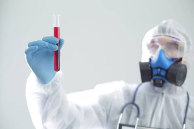 Koruyucu giysili bir adam elinde bir test tüpü tutuyor. Coronavirüs 'e karşı açık aşı kavramı