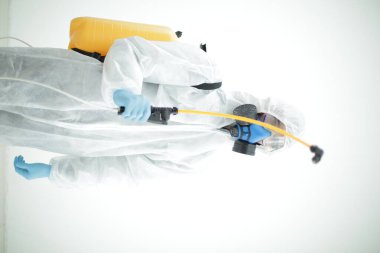 Koruyucu giysili, dezenfeksiyon silindirli bir adam.